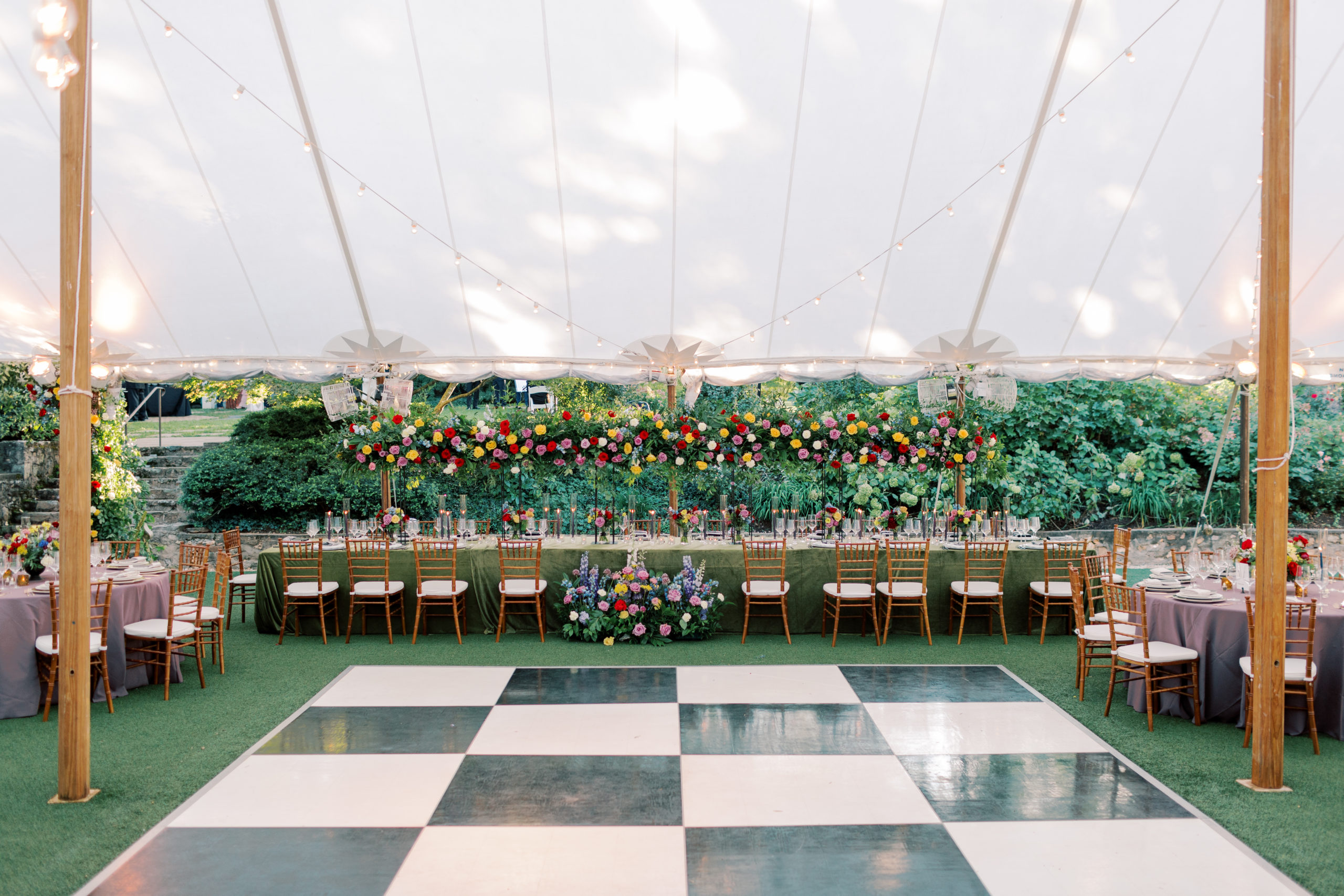 photo of large brilliant florals above a lush long table and a black and white checkered dance floor