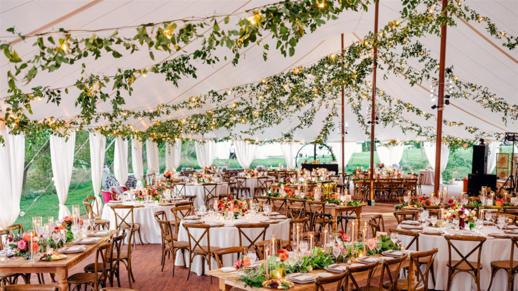 Rustic fall wedding tent with greenery canopy and dahlia centerpieces