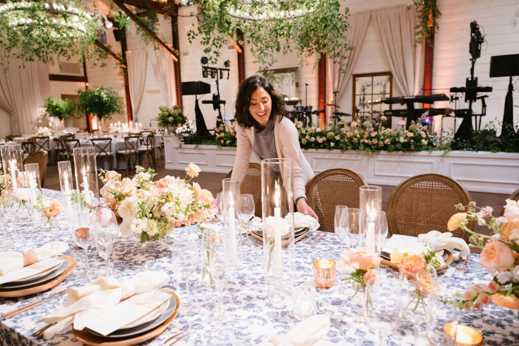A planner straightens place settings and places menus and place cards at a luxury wedding at Pippin Hill in Charlottesville virginia 