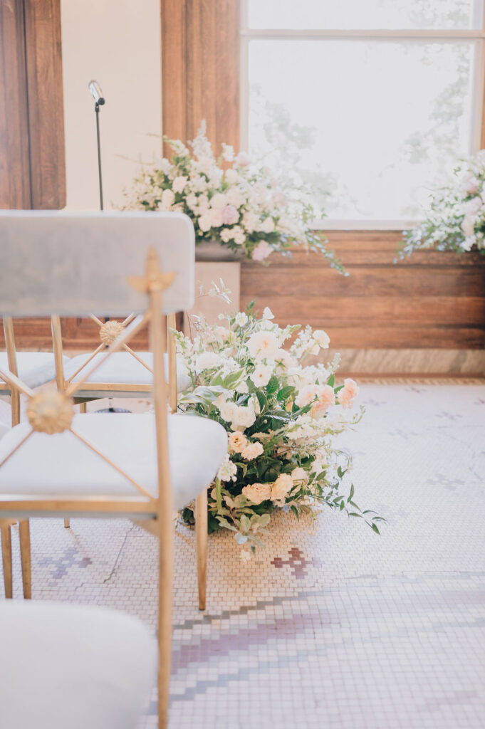 Indoor museum wedding ceremony in the historic Gibbes Rotunda. Elegant Charleston wedding inspiration with sage green velvet chairs and lush white floral arrangements.