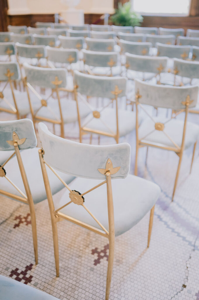 Indoor museum wedding ceremony in the historic Gibbes Rotunda. Elegant Charleston wedding inspiration with sage green velvet chairs and lush white floral arrangements.